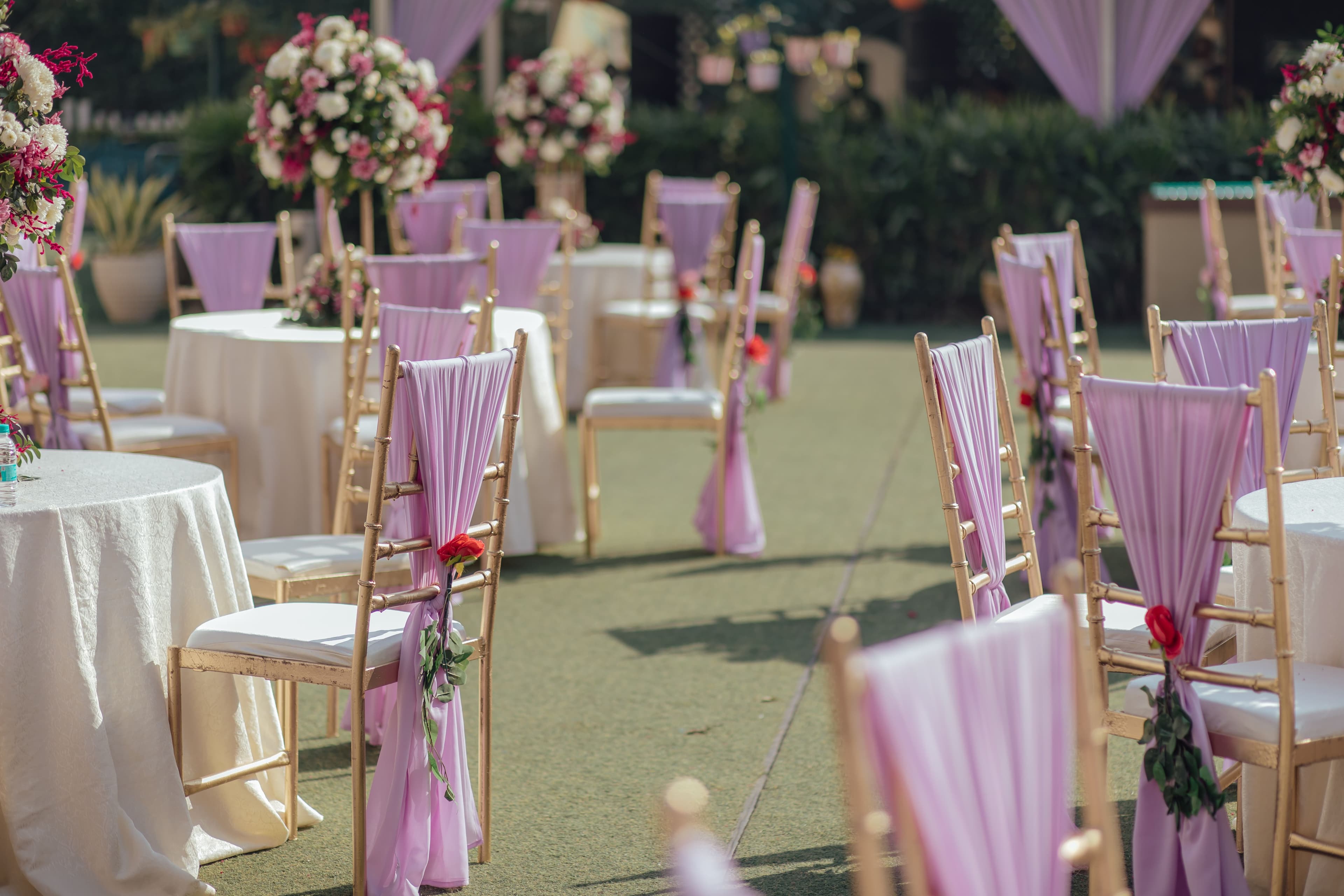 A sweeping, cinematic wide shot of a luxury outdoor wedding set at sunset on a grand, manicured lawn.