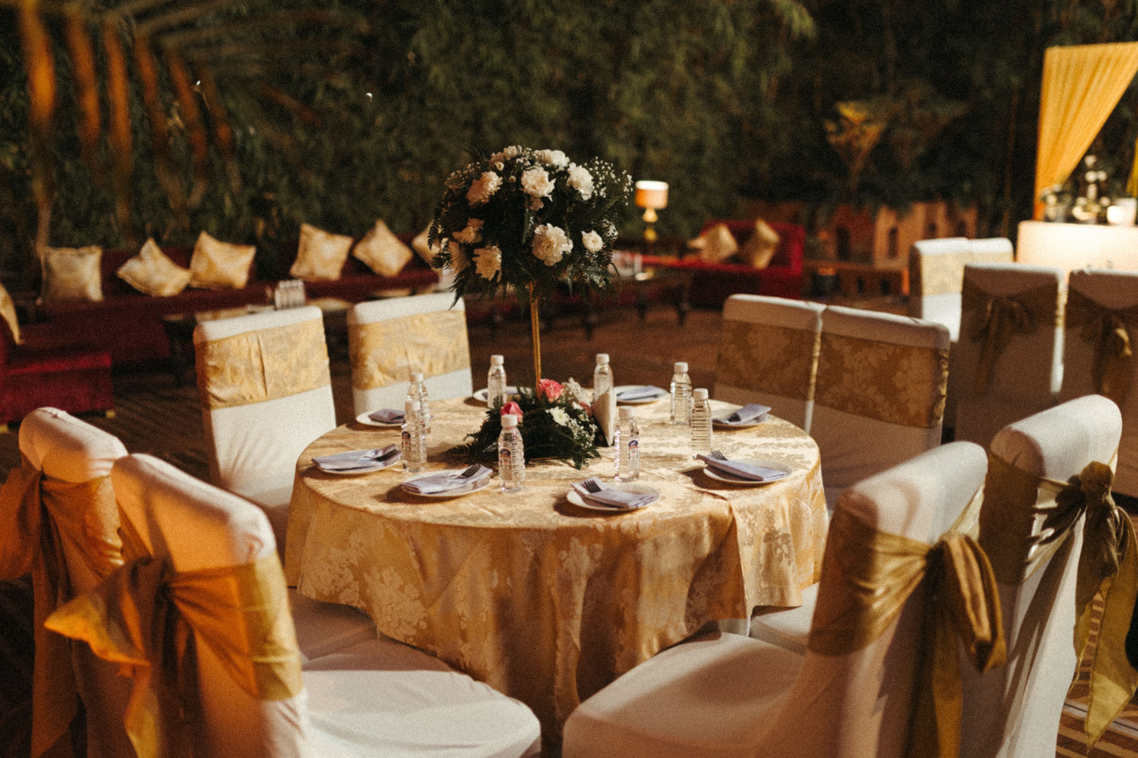 A sweeping, cinematic wide shot of a luxury outdoor wedding set at sunset on a grand, manicured lawn.